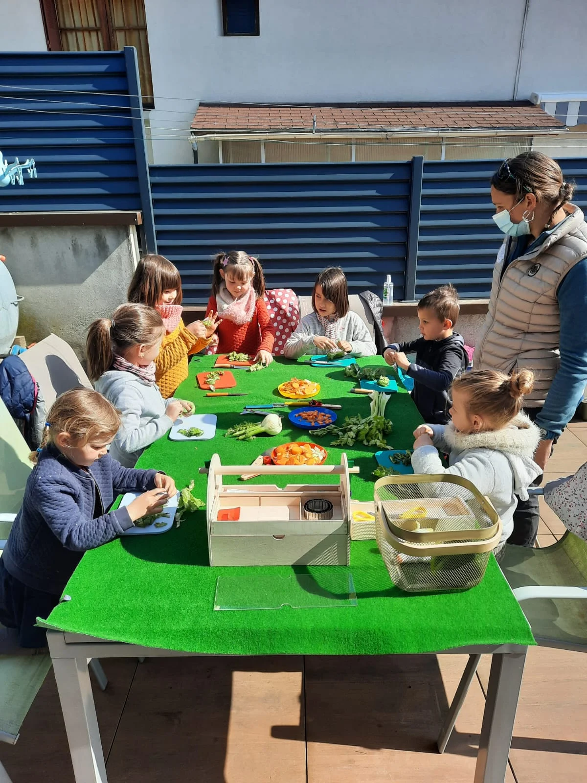 Enfants au contact d'un mouton noir avec Camille lors d'un atelier en plein air
